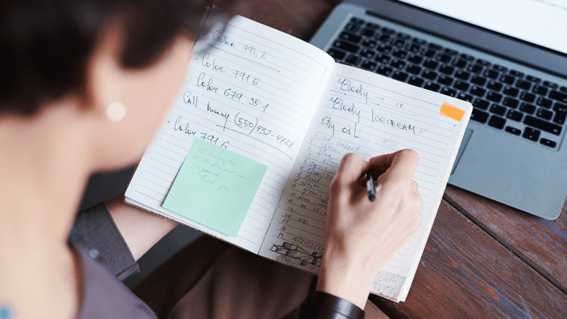 UMKM mencatat transaksi keuangan di buku catatan dengan laptop terbuka